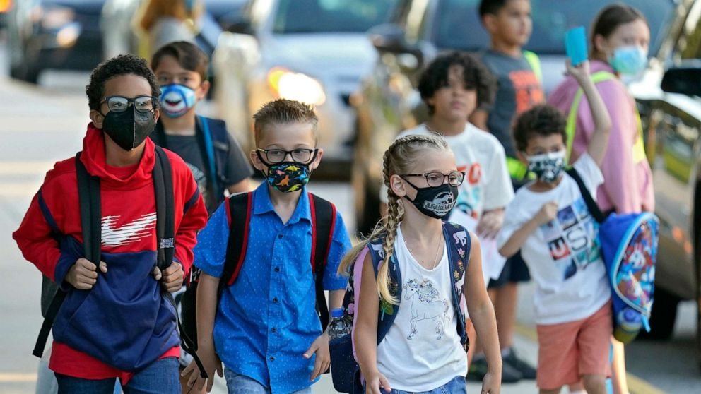 Elementary school students wearing masks on their way into school